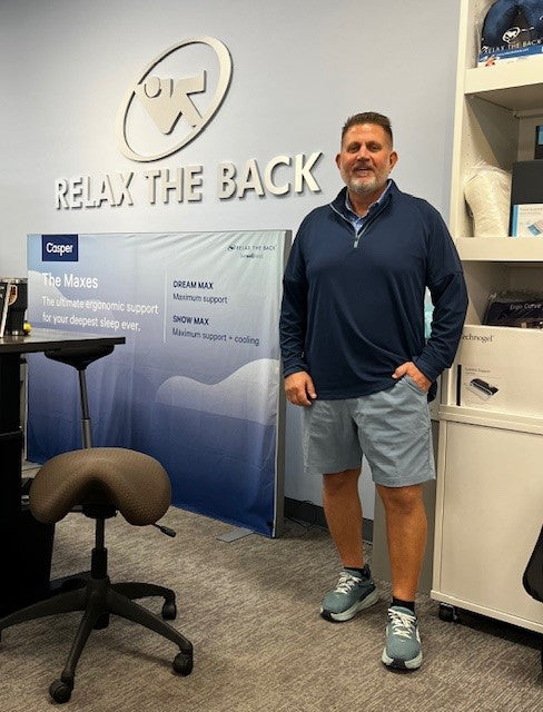 Man standing in a store with 'Relak the Back' sign and Casper product display.