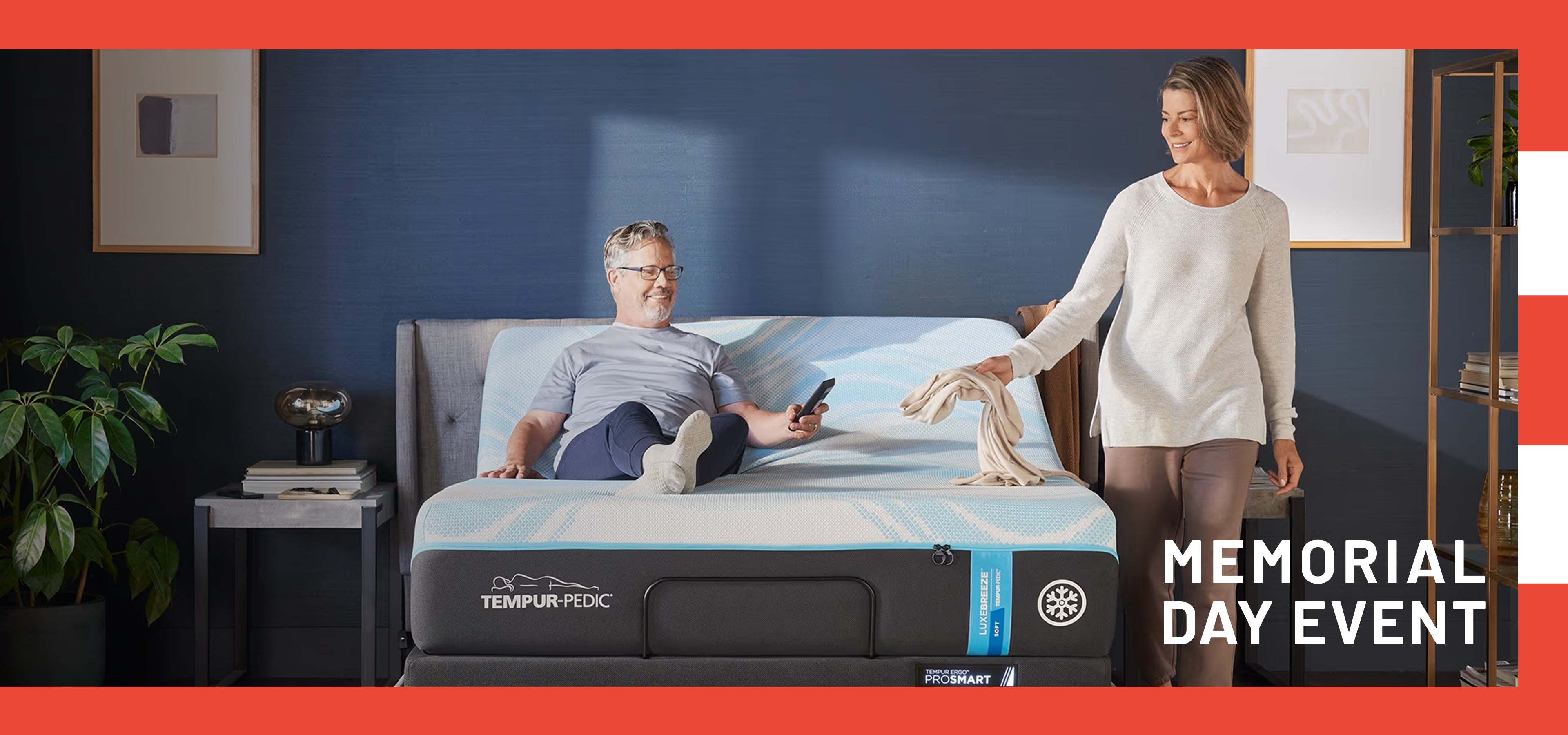 Person using a smartphone on a Tempur-Pedic mattress with a woman standing beside them, in a room setting.