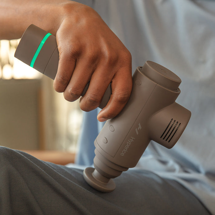 A man using the Hypervolt 2 Handheld Massager with Bluetooth by Hyperice® on  his thigh.