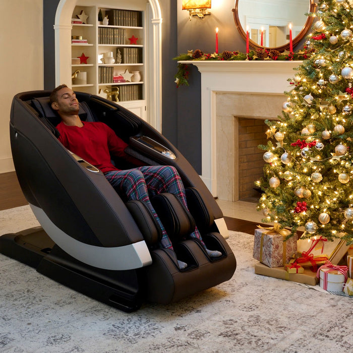 Man using the Human Touch Super Novo Massage Chair in a home with a Christmas Tree in the background
