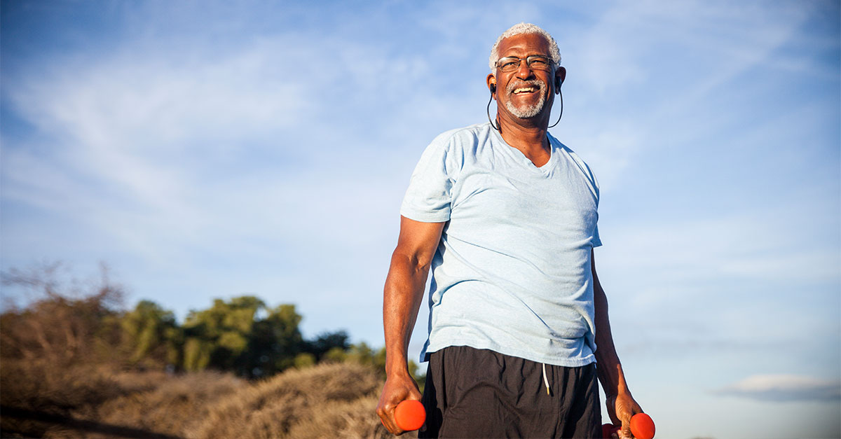 Elderly man with weights exercising outdoors