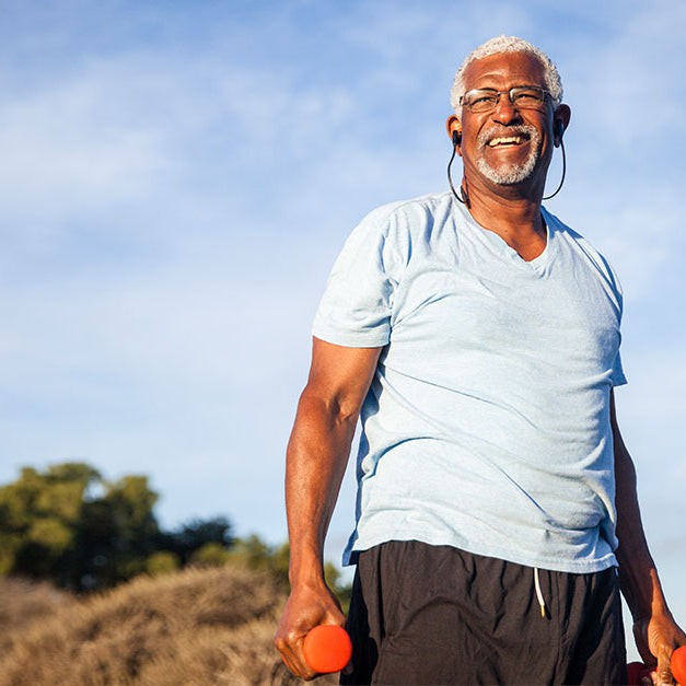 Elderly man with weights exercising outdoors