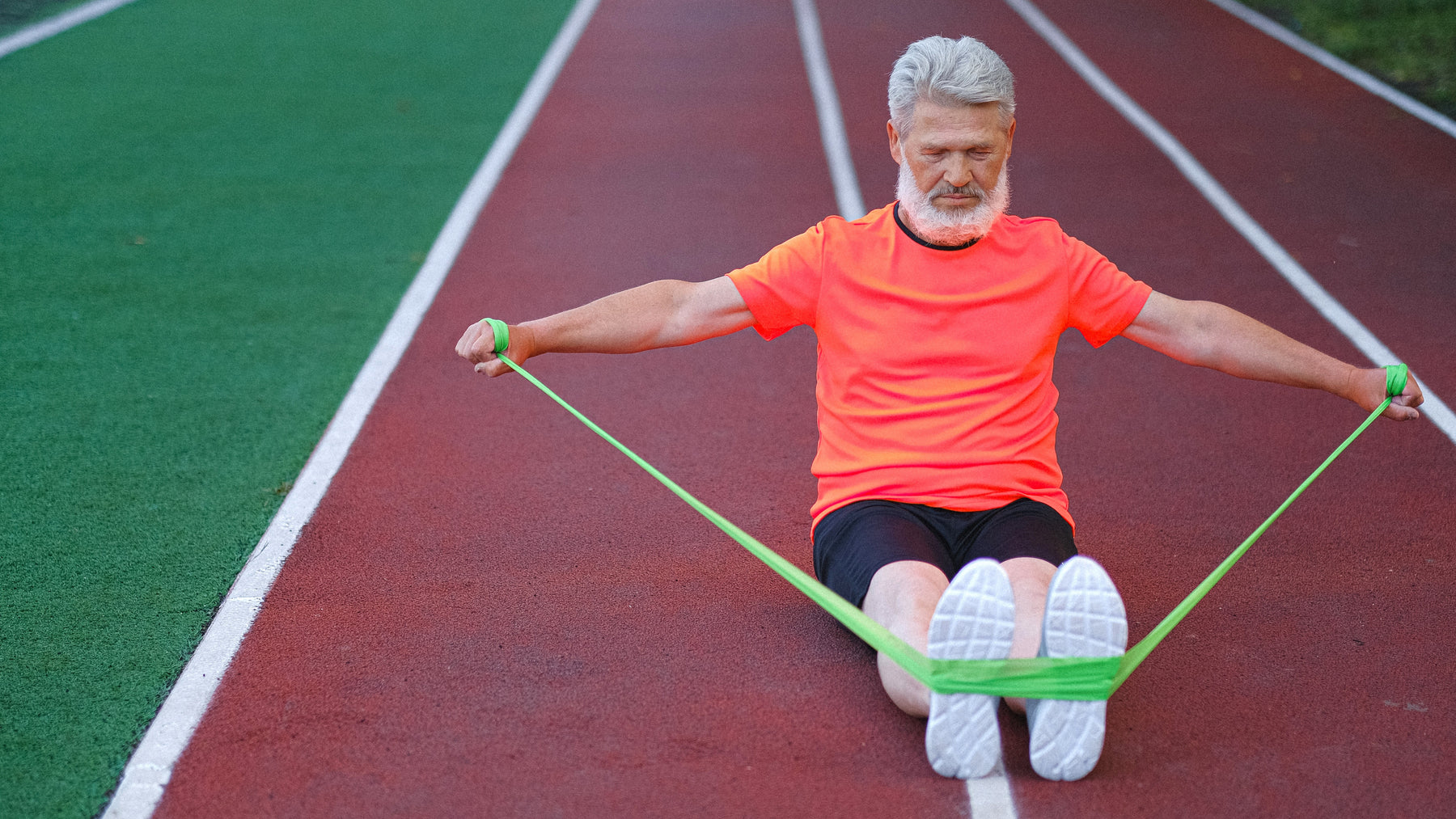 Man in an orange shirt stretching on a running track