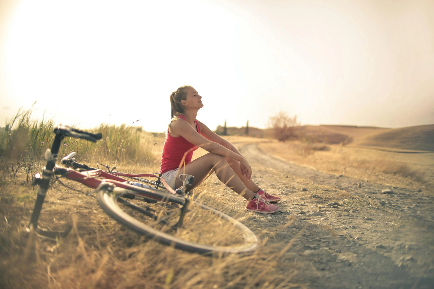 Woman sitting next to her bike on a dirt road