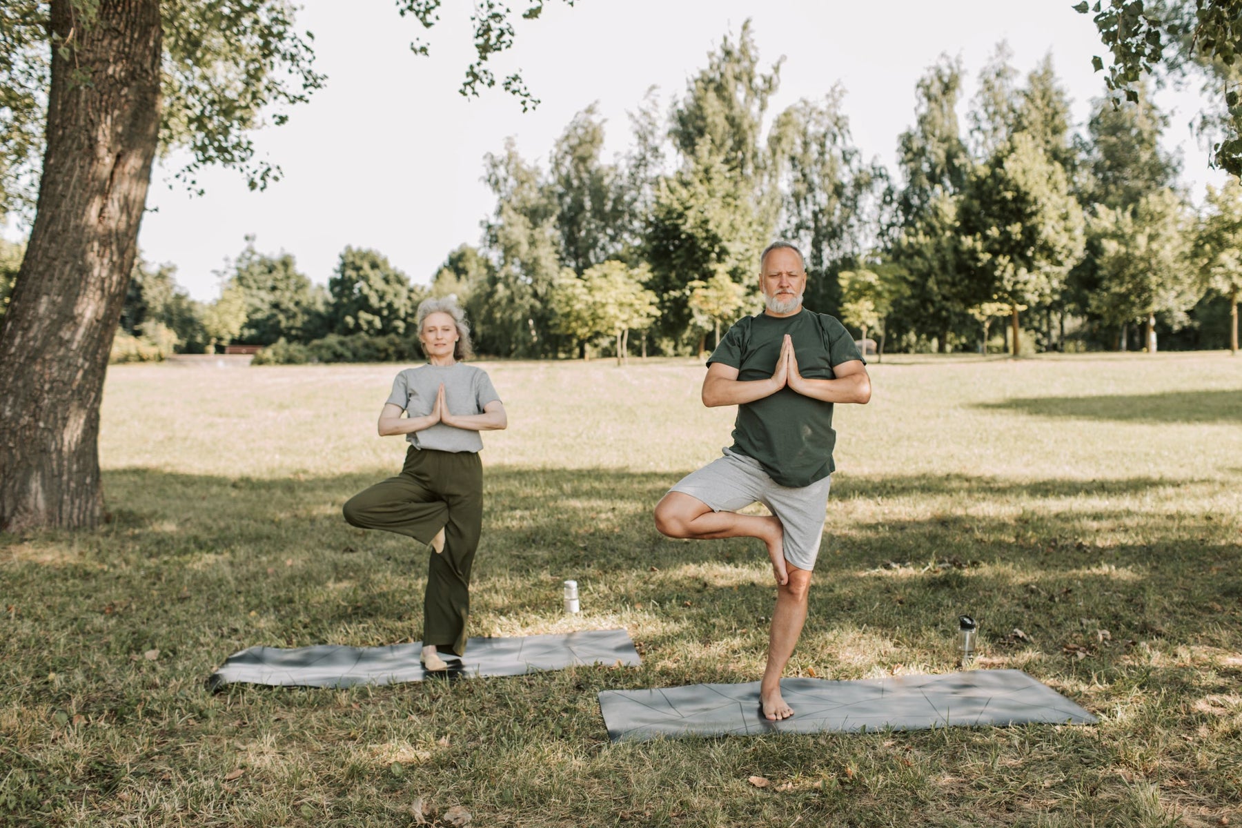 Couple practicing yoga in a park