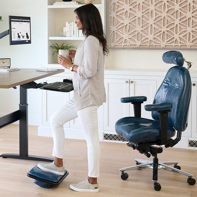 Woman standing at a desk with a blue chair 