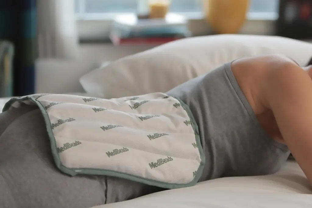 A woman using a moist heat pad on her back