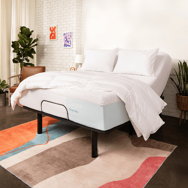 White adjustable bed in a bedroom setting with pillows and a blanket.