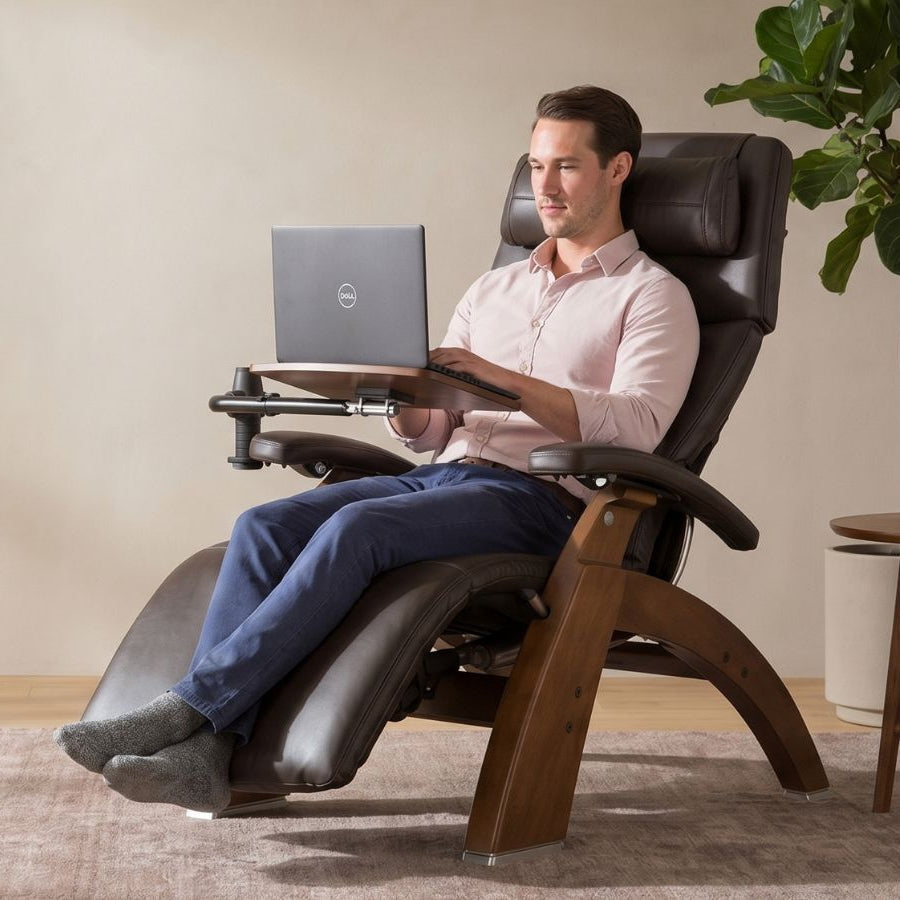 Man using a laptop on a recliner chair in a home setting