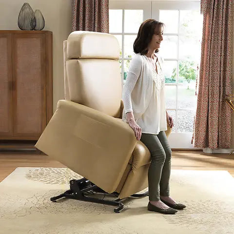 A woman using the lift function on a beige zero gravity lift chair.