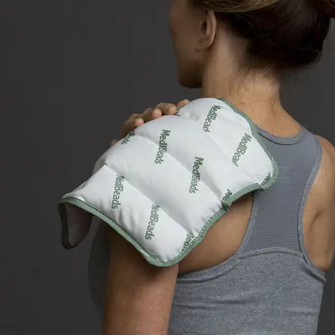 Woman leaning against a wall with a Flexi Kold cold pack in a kitchen.