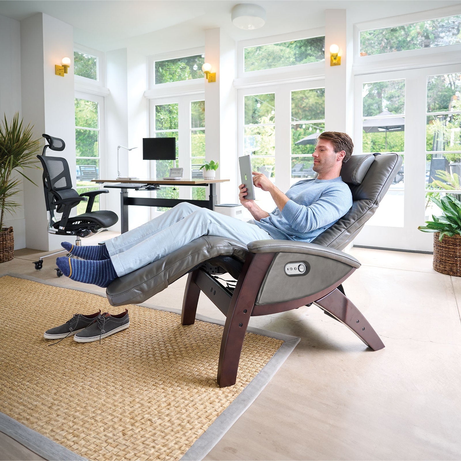 Man relaxing in a modern recliner chair in a bright room with large windows.