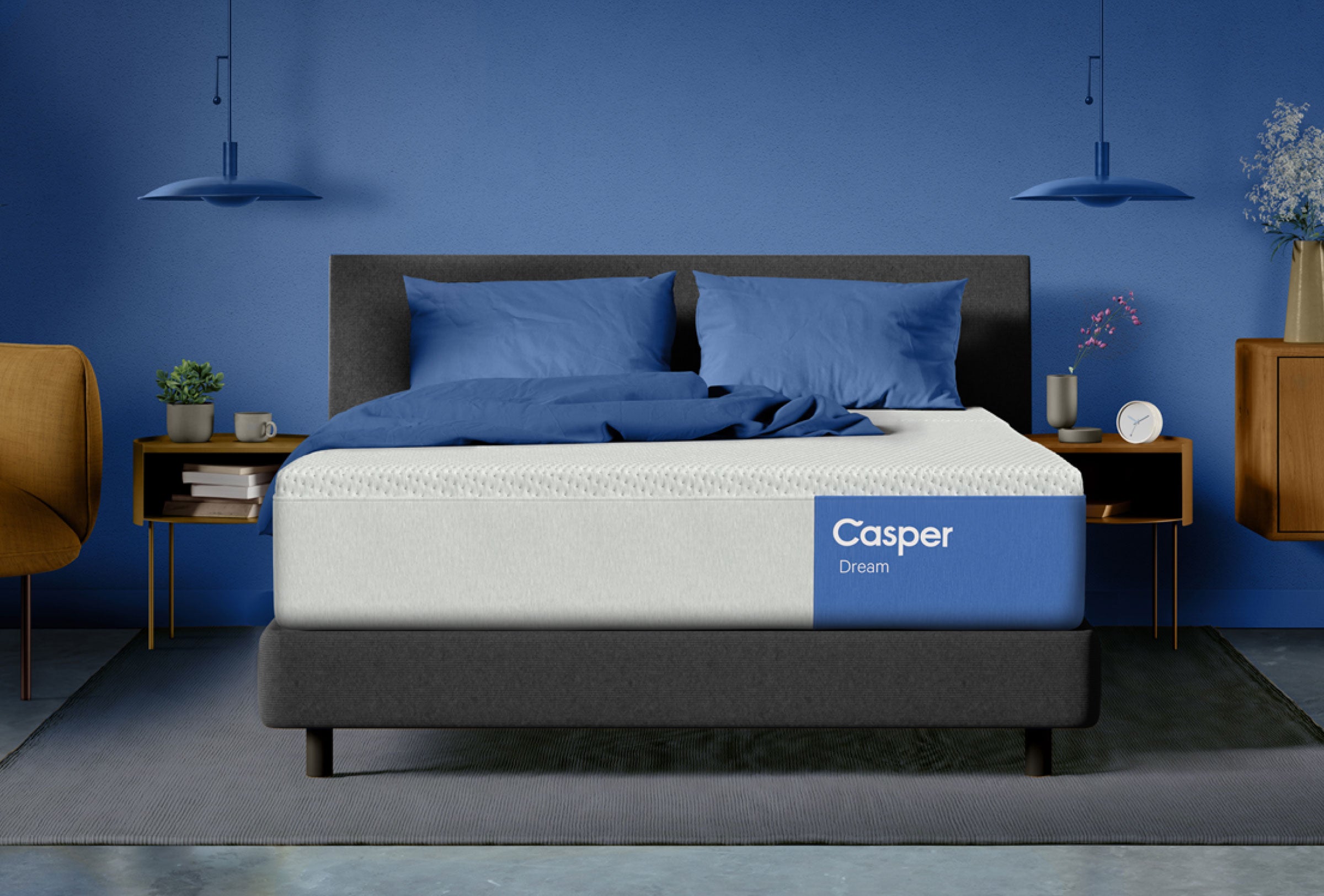 Casper Dream mattress on a dark platform bed with blue bedding, set in a modern bedroom with blue walls, pendant lights, nightstands, and decorative accents.