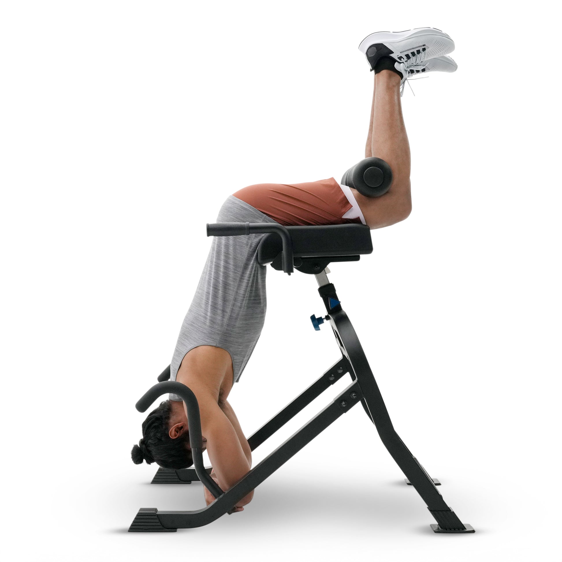 A person performing a headstand on a black leg extension exercise machine against a plain white background.