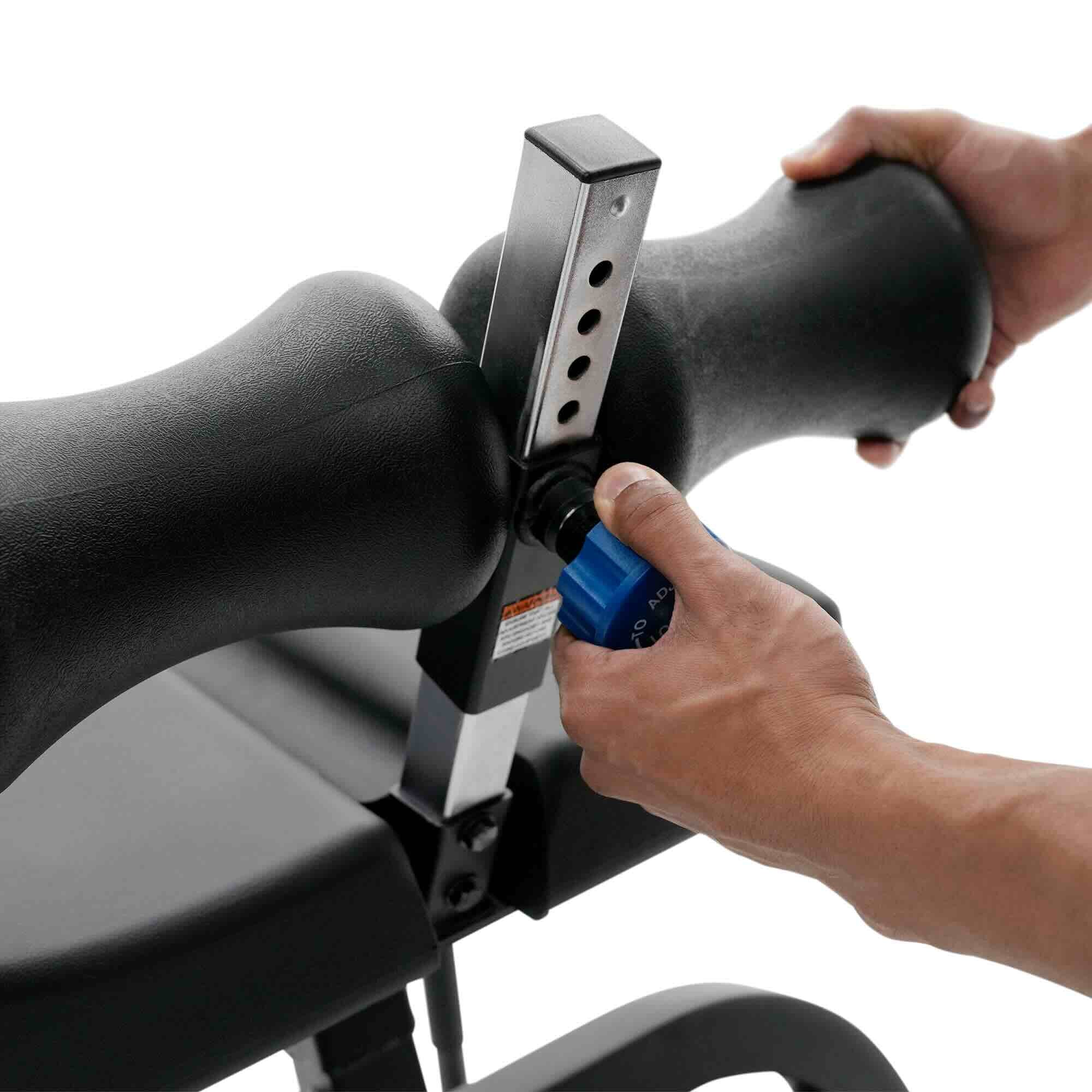 Close-up of a person adjusting a black adjustable bench pad or support arm on exercise equipment, with both hands visible against a white background.