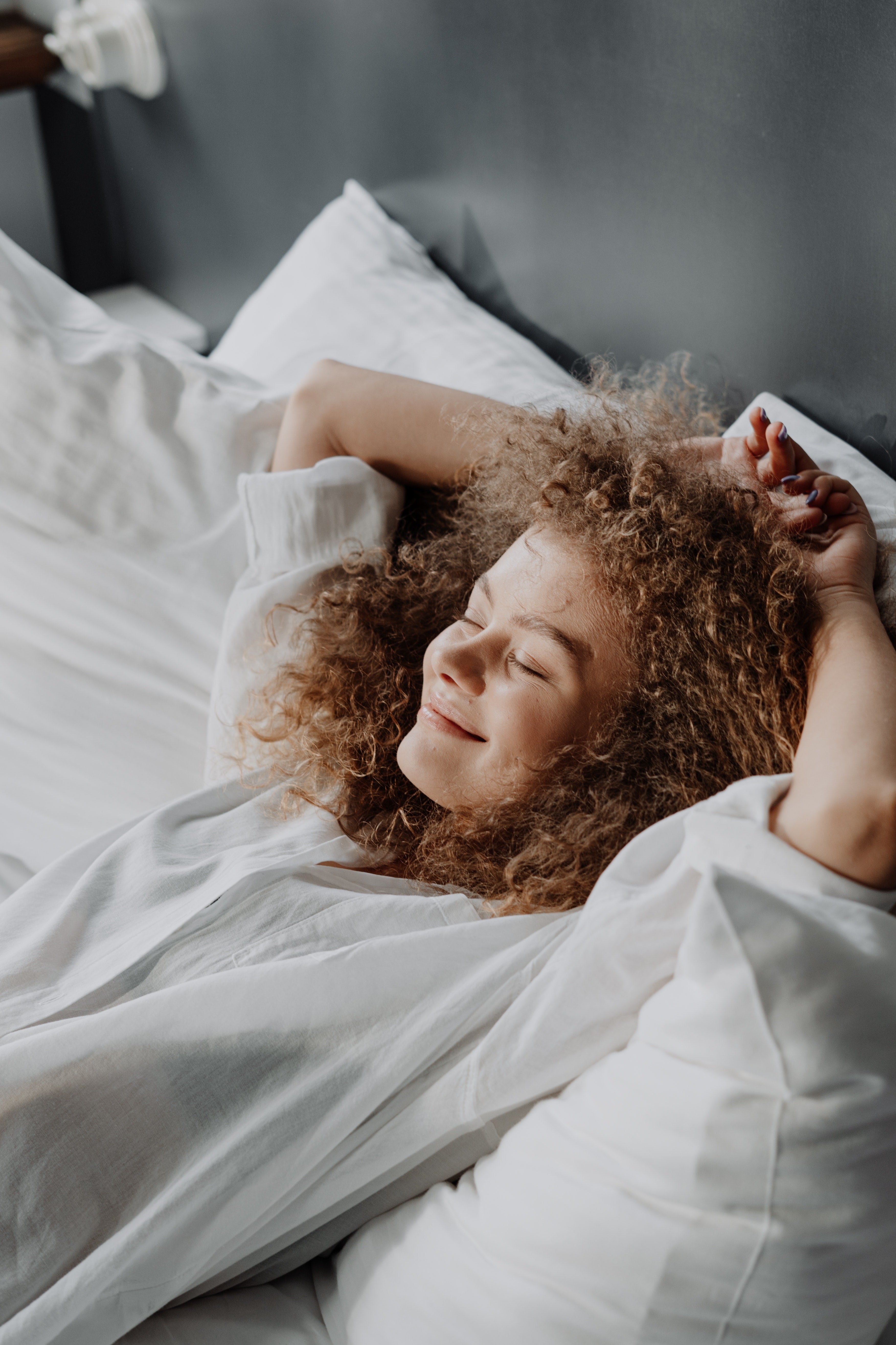 Woman laying in bed with her arms stretched above her head