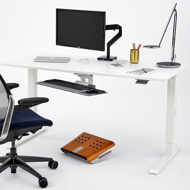 Modern office setup with a white desk, chair, computer monitor, keyboard, and footrest.