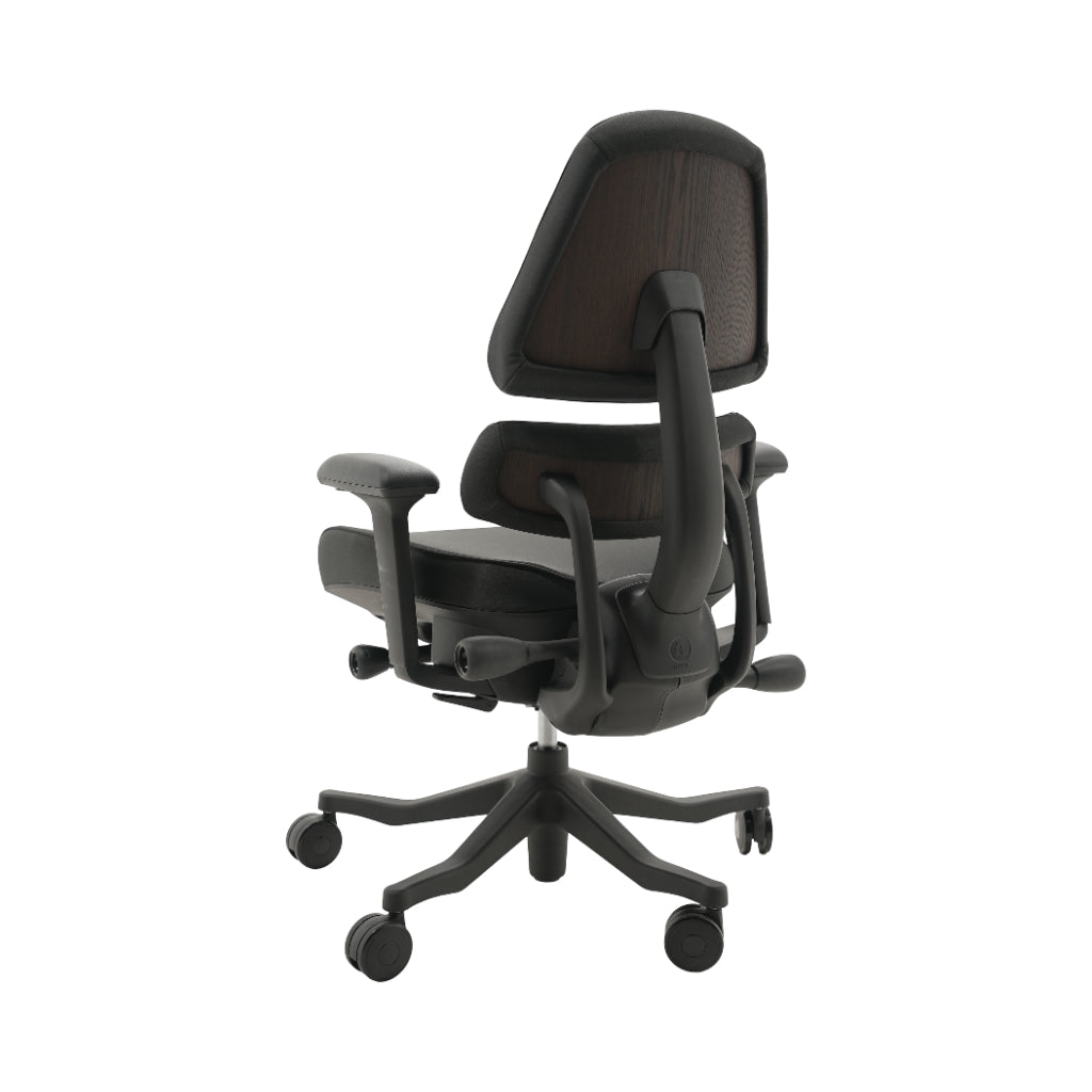 An ergonomic office chair with a high back, adjustable armrests, and a four-wheel base, shown from a rear angle on a white background.