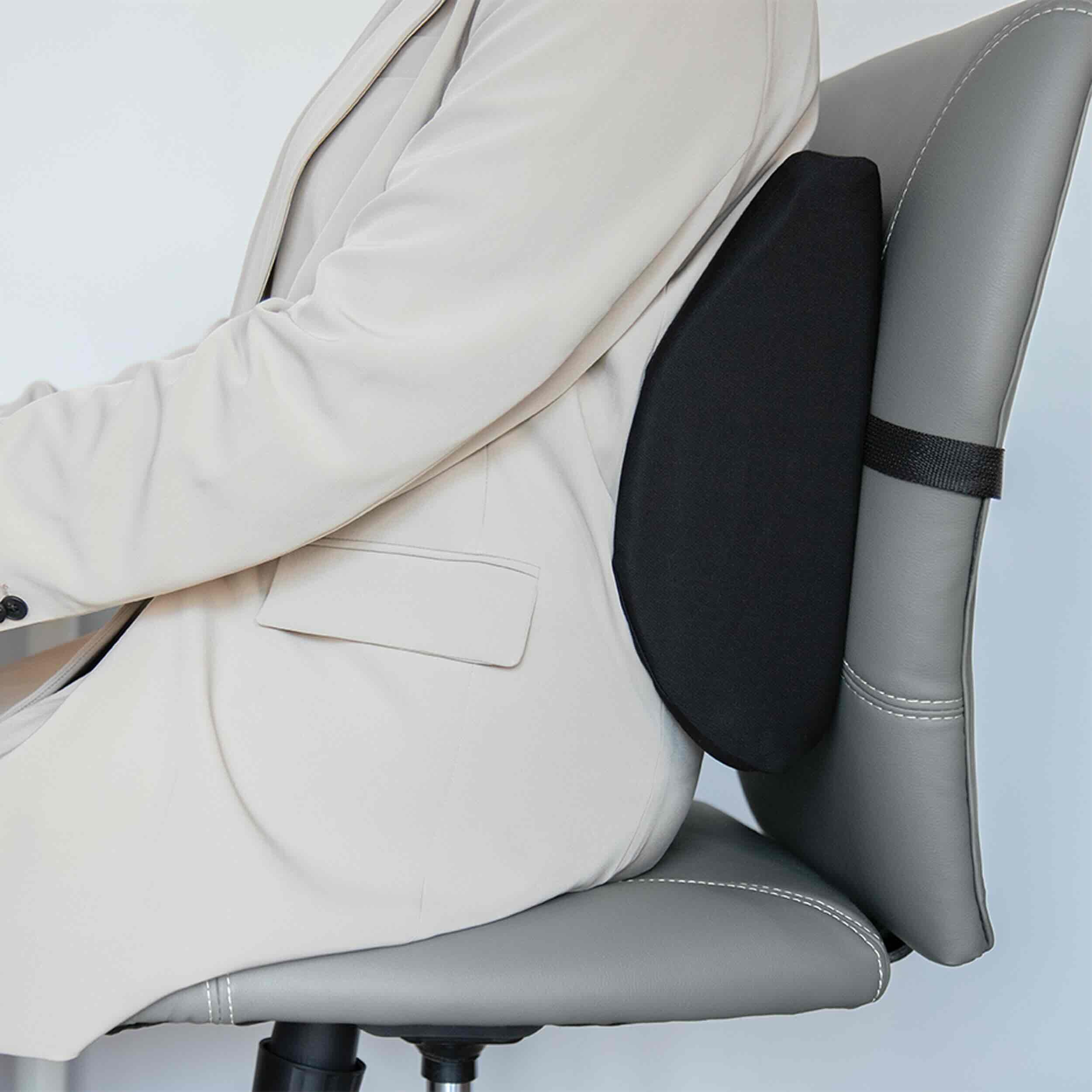 A person in a light beige blazer sits in a gray office chair, demonstrating the use of a black lumbar support cushion attached to the chair's backrest.