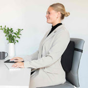 Person sitting at a desk with a backrest pillow, smiling.