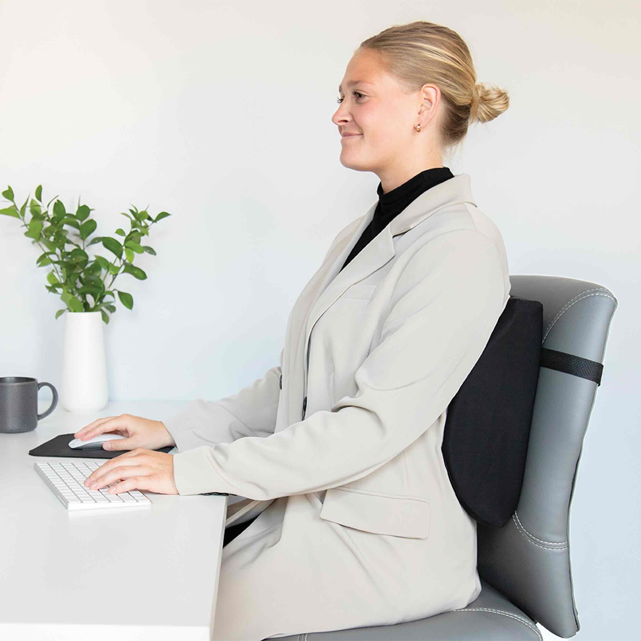 Person sitting at a desk with a backrest pillow, smiling.