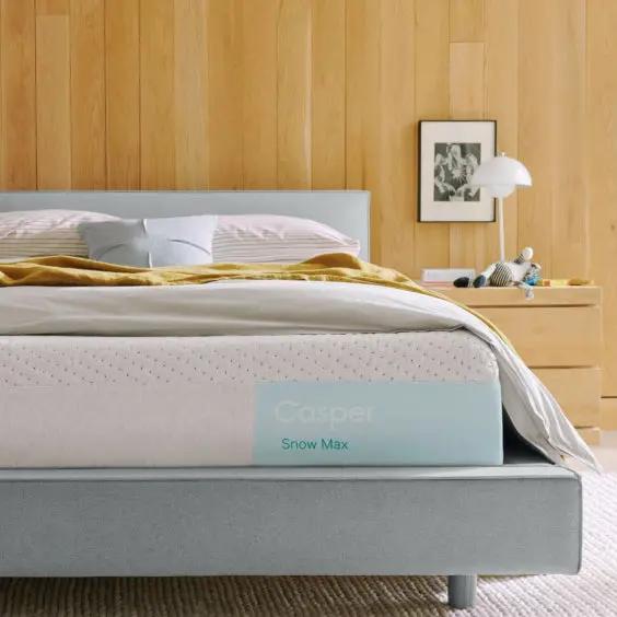 Casper Snow Max mattress on a bed with a wooden headboard and nightstand.