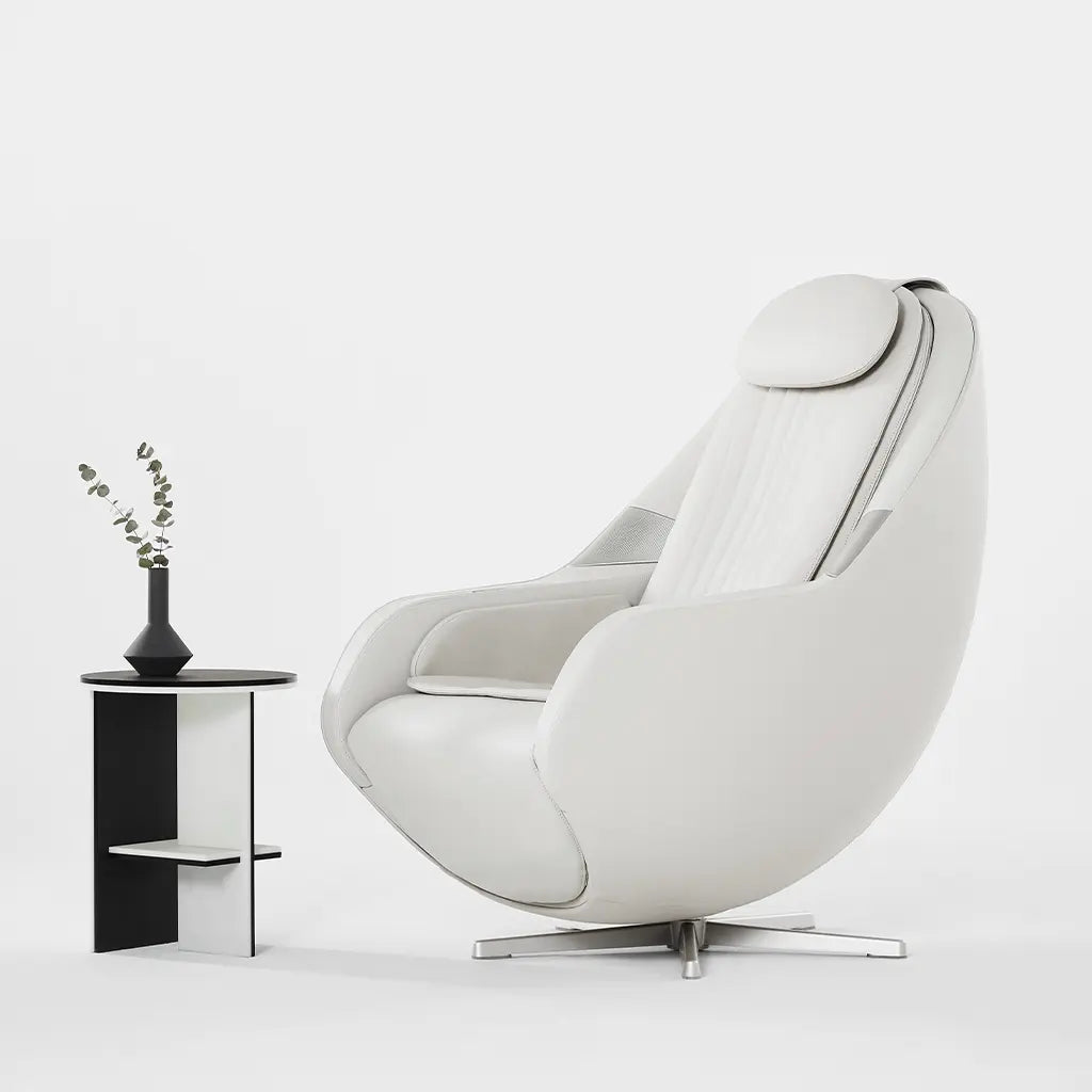 White armchair with a small black side table and plant on a white background