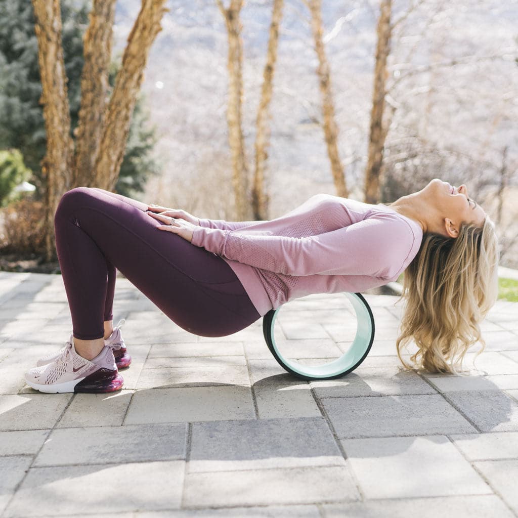 A woman using the Chrip Wheel on her back outdoors