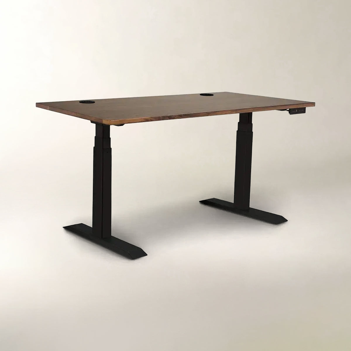 A modern standing desk with a rectangular brown wood-grain top and black metal T-style legs, shown on a neutral light gray studio background.