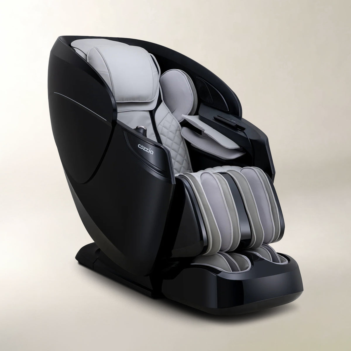 A modern cordless massage chair in black and light gray, shown from a three-quarters angle against a neutral beige background. The brand name 'Cozzia' is visible on the side of the headrest.