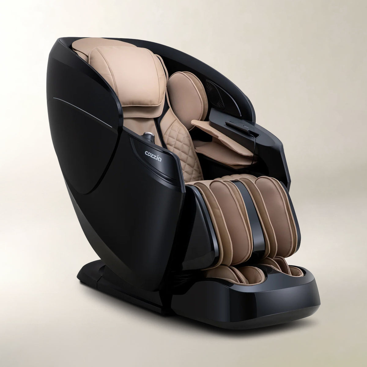 A modern massage chair with a glossy black outer shell and beige/tan padded interior, shown on a clean light beige studio background. The brand name 'Cozzia' is visible on the side of the chair.