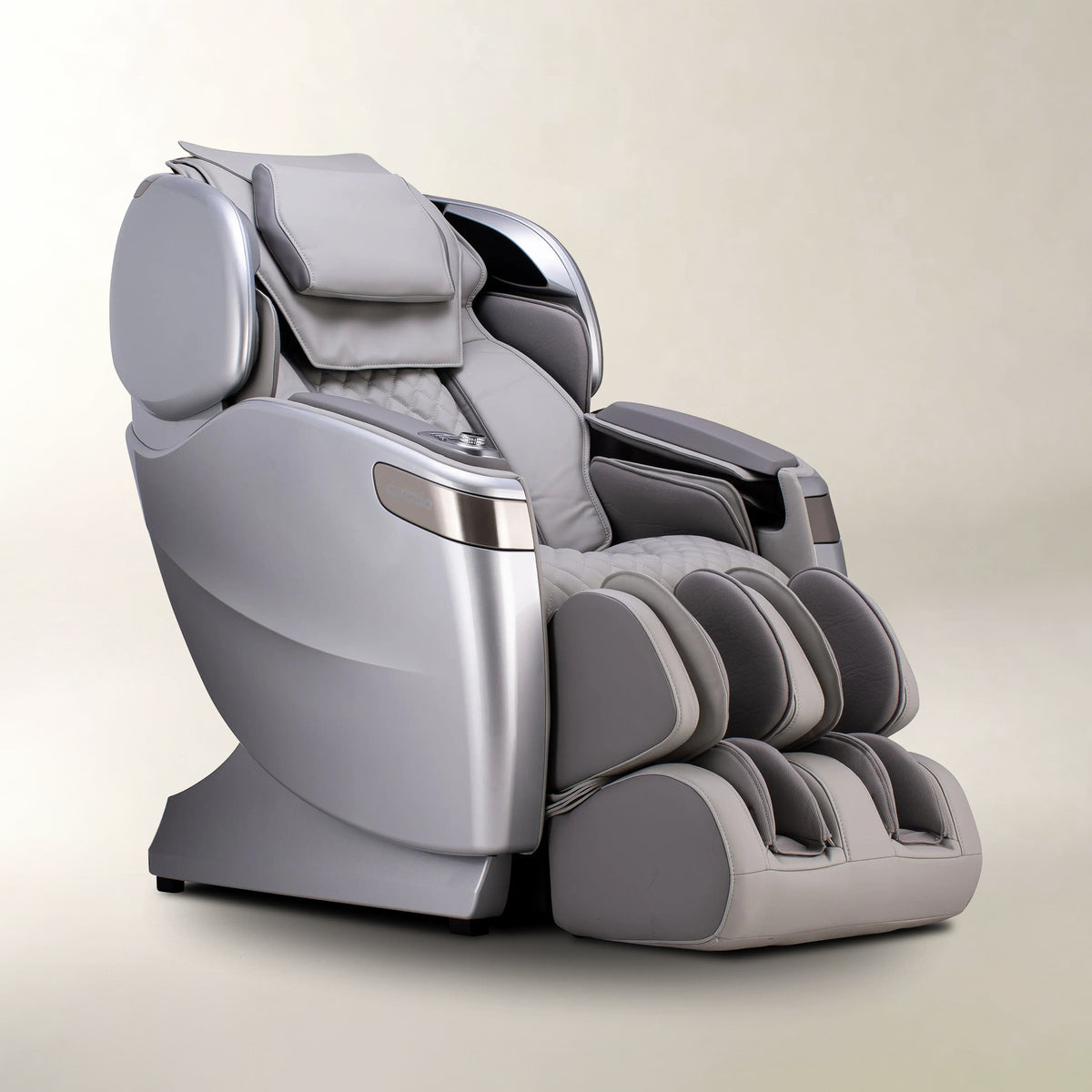 A modern gray and silver automatic massage chair with a padded headrest, adjustable armrests, and segmented foot massager pods, shown on a neutral beige background.