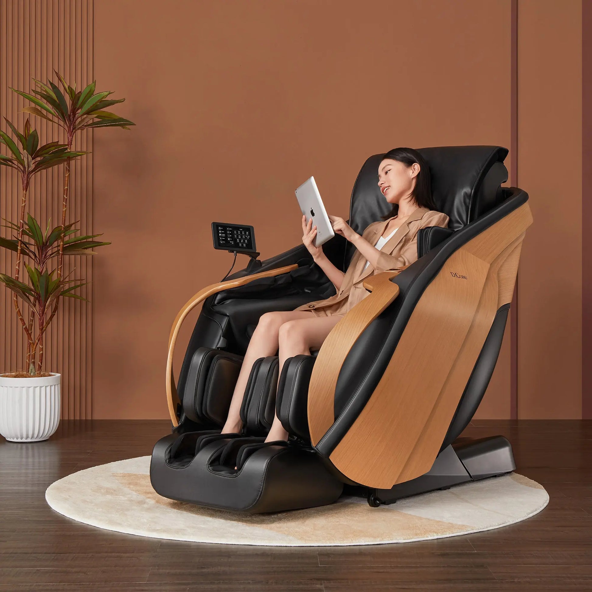 Woman using a tablet while sitting in a massage chair with a plant in the background