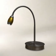 A modern gooseneck desk lamp with a matte black flexible arm and a round base, featuring a metallic gold shade, set against a plain light beige background.
