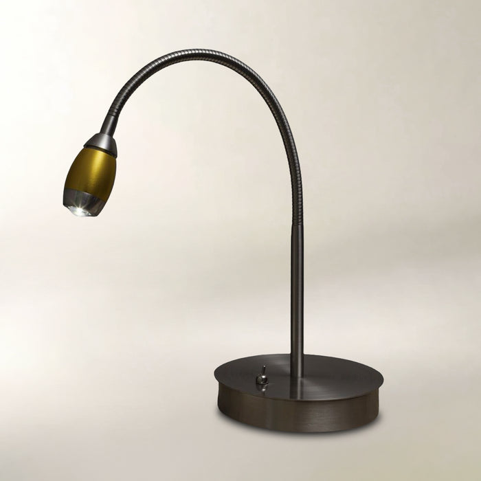 A modern gooseneck desk lamp with a matte black flexible arm and a round base, featuring a metallic gold shade, set against a plain light beige background.