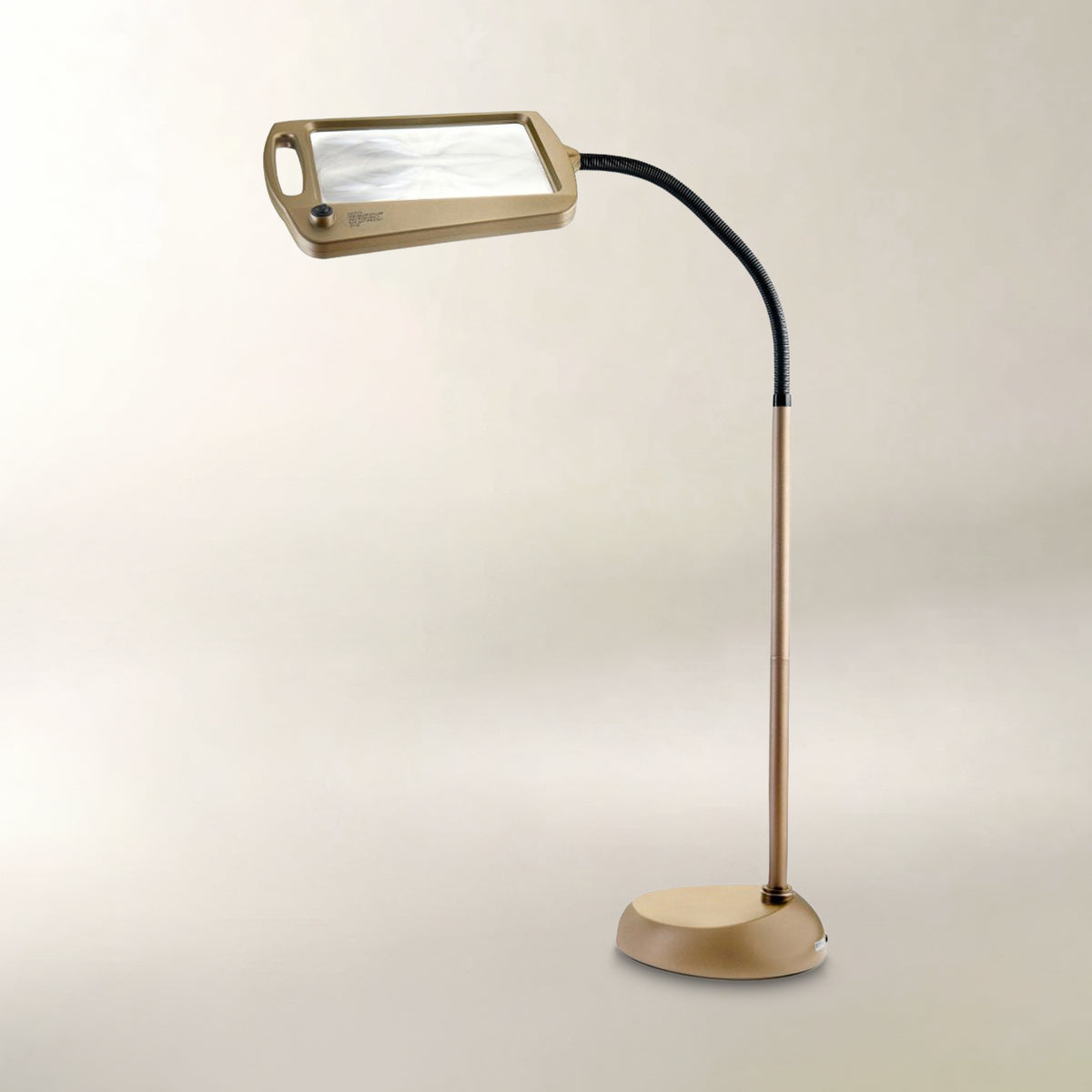 A modern floor lamp with a rectangular magnifying glass head, a flexible black neck, and a round metallic gold base, set against a plain light beige background.