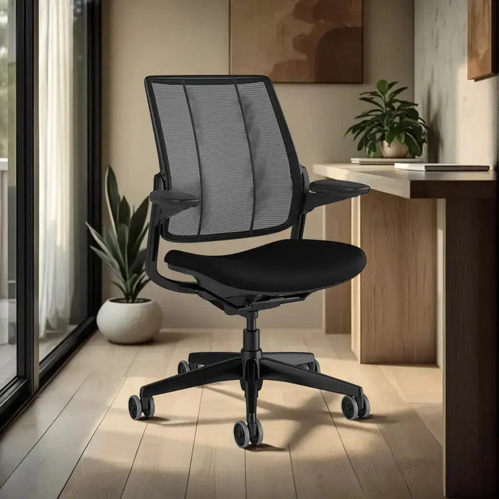 Diffrient Smart Chair in black shown in a home office with wooden floors, abstract art and plants in rounded pots.