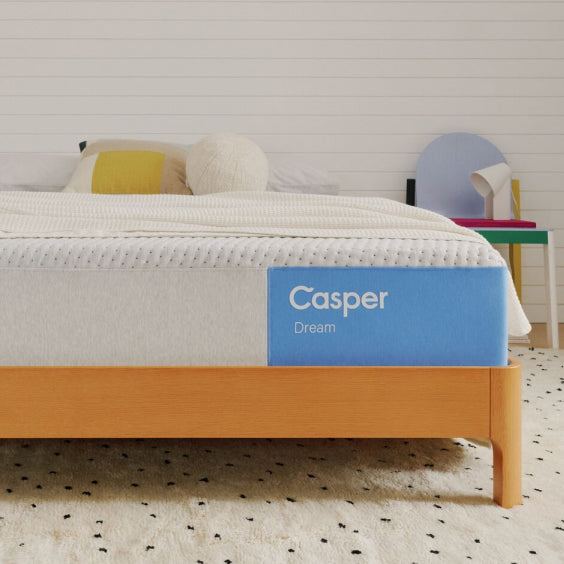 Casper mattress on a bed with a wooden frame in a room setting.
