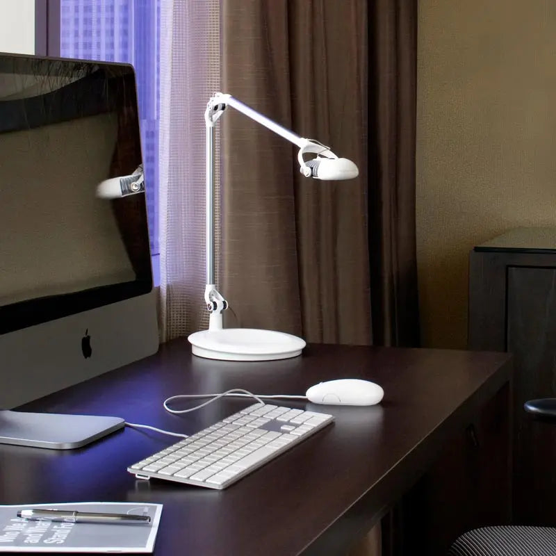 The Element Adjustable Desk Lamp in white shown on an office desk.