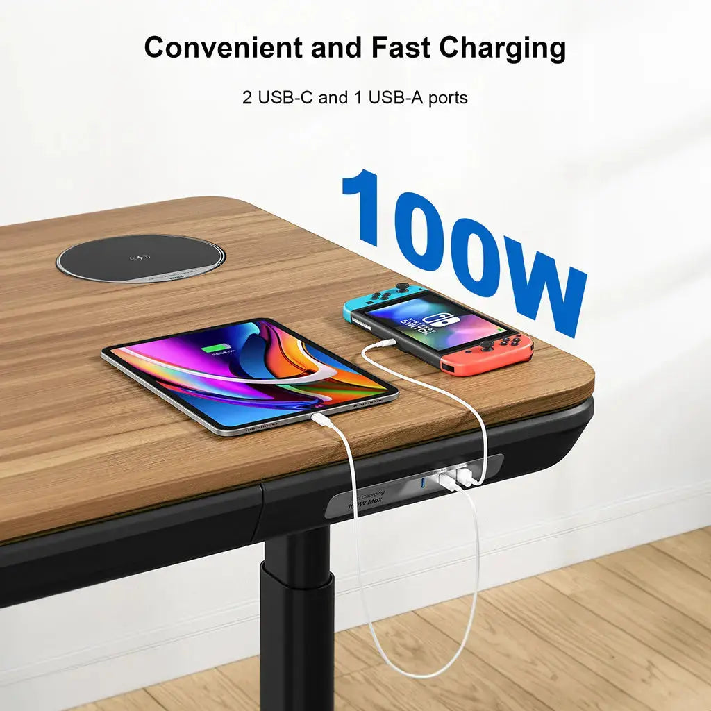 Close-up of a walnur standing desk charging a tablet and gaming device via built-in USB ports.