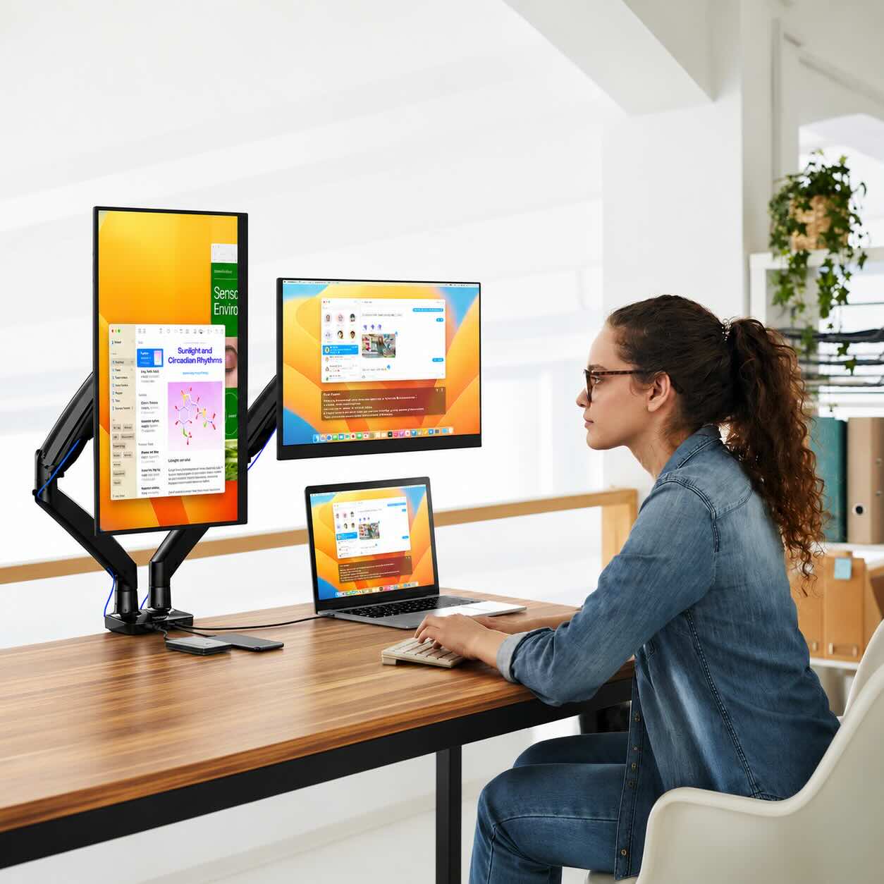 Person working at a desk with multiple computer monitors in a bright office setting