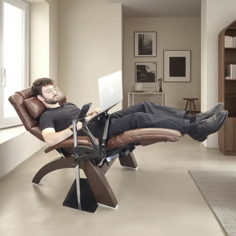 A man is sitting in a recliner using the Ergonomic Laptop and Tablet Stand in a living room setting.