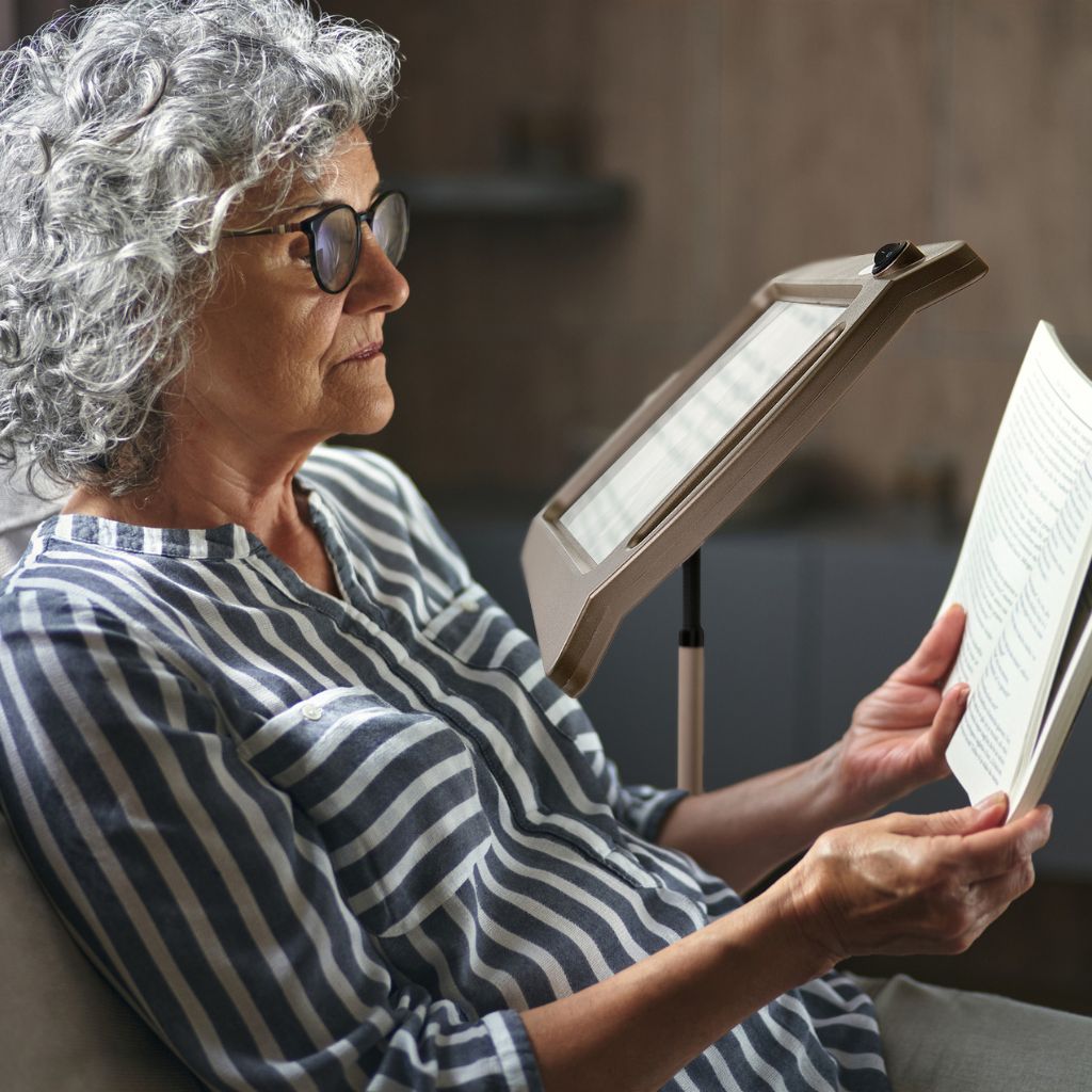 Woman reading a book with a light stand in a cozy indoor setting