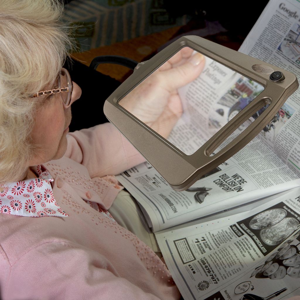 Person using a handheld magnifying glass to read a newspaper