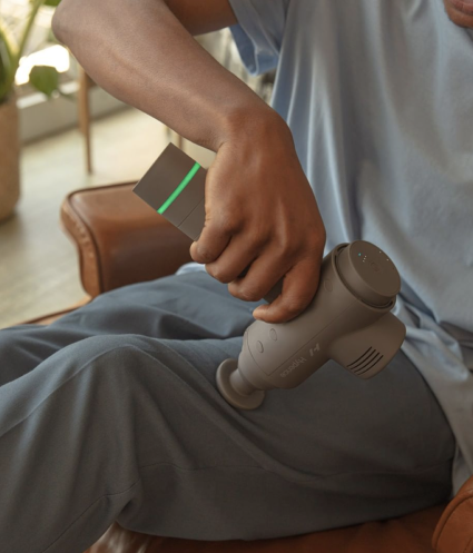An individual using the Hypervolt massager on their leg