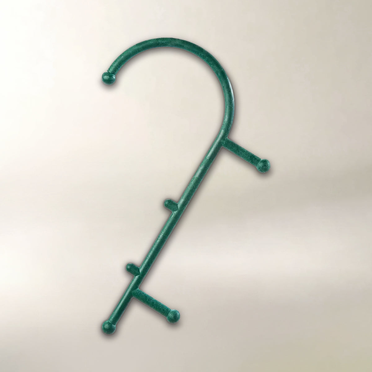 A green manual massage cane with three horizontal pegs and small ball tips, shown against a plain light beige background.