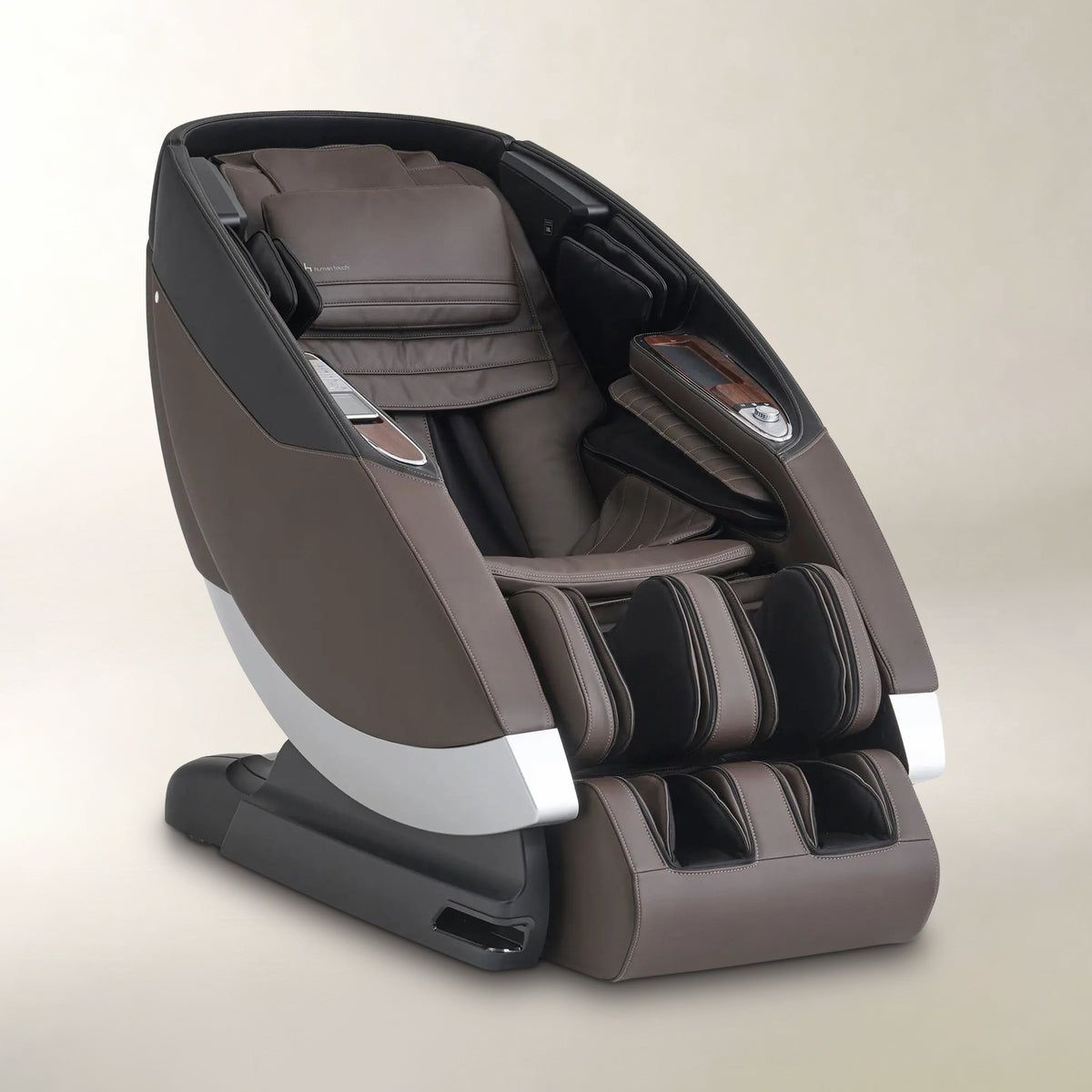 A modern massage chair in brown and black with silver accents, shown from a three-quarters angle on a neutral beige background.
