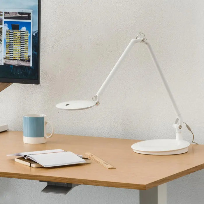 The Humanscale Element Disc Light in white shown on an office desk.