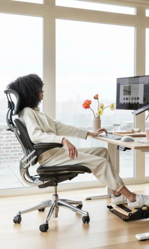 Person using a computer at a desk with a large window in the background