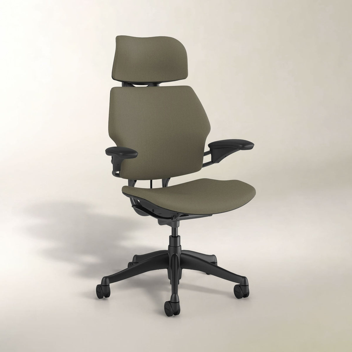 An ergonomic office chair with a high backrest, matching headrest and seat cushions in a muted olive green fabric, and a black five-star wheeled base, shown against a plain light beige studio background.